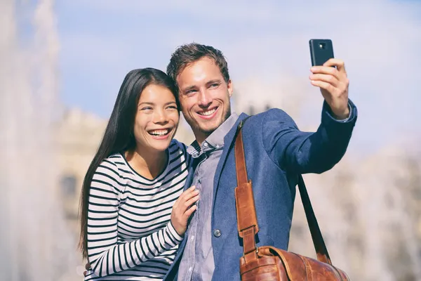 Selfie turystów para robi zdjęcia z telefonu w słoneczny dzień w Europie trave miasta przeznaczenia. Szczęśliwa Azjatka, biały mężczyzna za pomocą telefonu zdjęcie na wakacje. — Zdjęcie stockowe