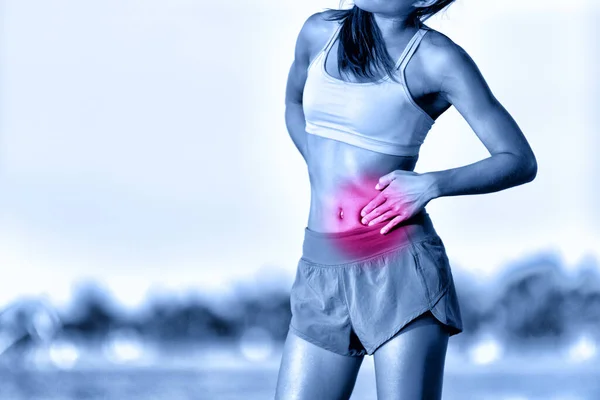 Gyomorfájdalom oldali öltés fáj nő futó, amelynek görcs edzés közben fut a strandon. Női sportoló gyomortáji fájdalommal futás közben. — Stock Fotó