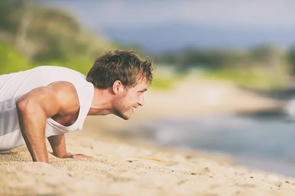 Fit hombre entrenamiento en la playa haciendo flexiones entrenamiento verano fitness estilo de vida. — Foto de Stock