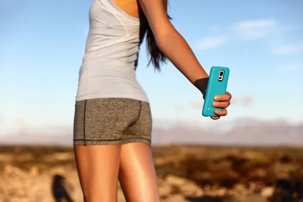 Fitness girl taking selfie of her butt to show off toned glutes from all the workout and training. Proud girl using phone on social media. Body image issue. — Fotografia de Stock