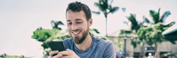 Homem Smartphone usando mensagens de texto SMS de telefone celular fora no fundo do verão. Panorama de banner de estilo de vida de jovens. Cara casual feliz sorrindo segurando celular usando o aplicativo para mídias sociais. — Fotografia de Stock