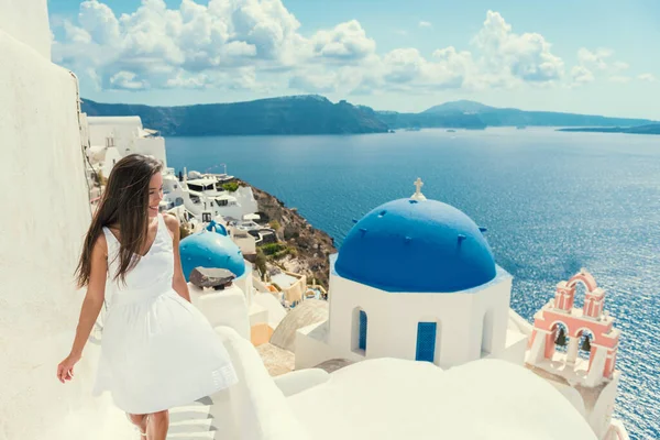 Santorini reizen toeristische vrouw op vakantie in Oia lopen op de trap. Aziatisch meisje in witte jurk een bezoek aan het beroemde witte dorp met de Middellandse Zee en blauwe koepels. Europese zomerbestemming. — Stockfoto