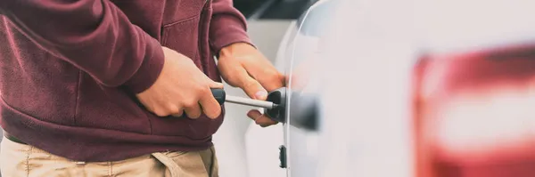 Robo de coche ladrón de hombre rompiendo en automóvil con herramienta para robar fondo panorámico de la bandera. — Foto de Stock