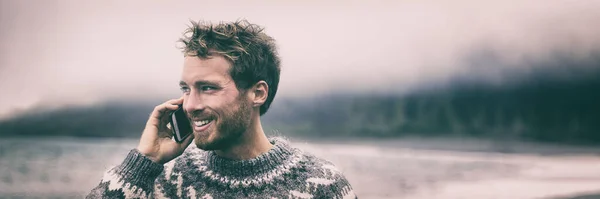 Homem de telefone no inverno chamando alguém no celular andando fora banner panorama. Jovem modelo sorridente segurando smartphone no fundo Islândia. Tecnologia móvel 5g. — Fotografia de Stock