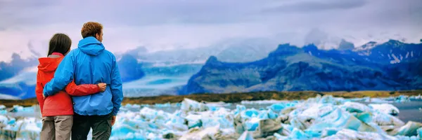 冰岛冰川景观游客夫妇在Jokulsarlon湖。冬季探险徒步旅行的人全景横幅背景. — 图库照片