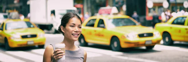 New York city pendla - asiatiska affärskvinna promenader till jobbet på morgonen pendling dricka kaffe kopp på NYC gata med gula taxibilar i bakgrunden banner. Människor pendlar livsstil. — Stockfoto