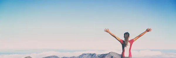 Winnende succes banner vrouw bereiken top doel met armen omhoog in de lucht panorama. Blauwe lucht achtergrond. Meisje leeft haar leven tot het uiterste vervullen van haar dromen - bucket list concept. — Stockfoto