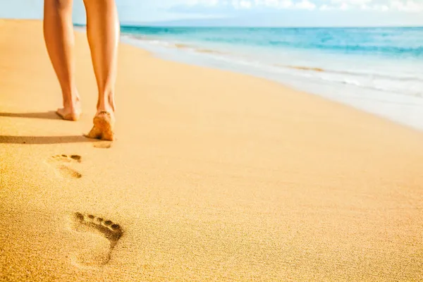 海滩女人的脚赤脚在沙滩上行走，日落时在金色的沙滩上留下脚印。 度假旅行自由人们在夏天放松. — 图库照片