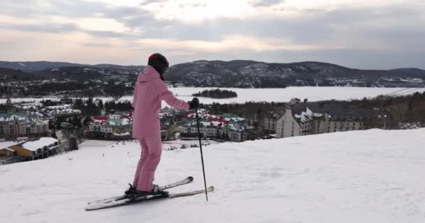 Esquí mujer. Esquí alpino - esquiador mirando montaña pueblo estación de esquí vista comenzando a esquiar cuesta abajo en nieve cubierta pista de esquí en invierno. Mont Tremblant, Quebec, Canadá — Vídeos de Stock