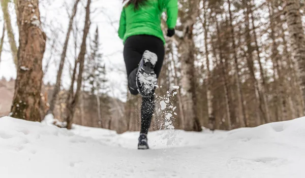 Tél fut a hóerdei természetben. Női futópálya futó hó téli erdő táj. Női terepfutó futás meleg ruhában. Felismerhetetlen futó - közelkép futócipőn — Stock Fotó