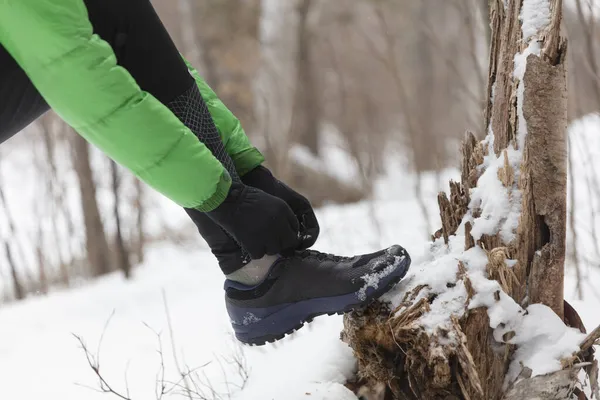 Winterlauf in verschneiter Waldnatur. Trailläuferin schnürt Schnürsenkel im Schnee in winterlicher Waldlandschaft. Langläuferin bis zur Unkenntlichkeit. Nahaufnahme der Laufschuhe — Stockfoto