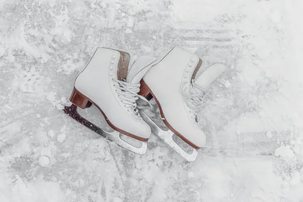 Figura pattinaggio donne pattini sdraiati al di fuori su bianco congelato ghiaccio vista dall'alto texture sfondo. Attrezzatura per sport invernali all'aperto — Foto Stock