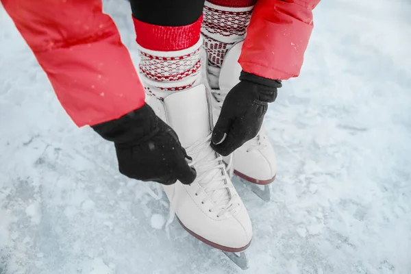 Patinaje sobre hielo mujer atando cordones de zapatos de patinaje artístico para ir a patinar en la pista. Gente del deporte de invierno. Primer plano de las manos y los pies. — Foto de Stock