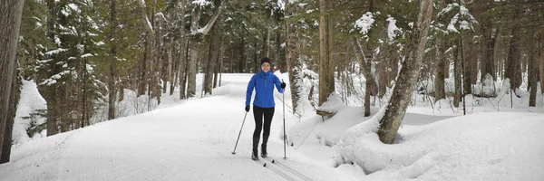 Woman Cross Country skiing Classic Style Nordic Skiing in Forest. Active girl in winter wonderland doing fun winter sport activity in the snow on cross country ski in beautiful nature landscape