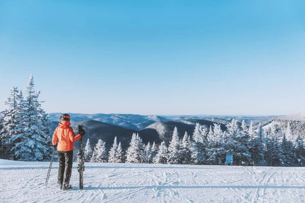 Vacances d'hiver Vacances de ski. Femme skieuse regardant les montagnes paysage nature à l'extérieur debout tenant des skis. Ski alpin piste de neige poudreuse blanche par temps froid — Photo