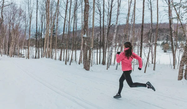 Nő fut a téli hóban. Futó kocog kint a hideg téli napon az erdőben. Alkalmas egészséges életmód fotó gyönyörű fiatal fitness modell. Lány fut teljes hosszában téli futócipő — Stock Fotó