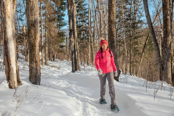 Χειμερινό χιονοπέδιλο. Snowshoeing ασιατική πολυφυλετική γυναίκα στο δάσος το χειμώνα για πεζοπορία στο χιόνι φορώντας χιονοπέδιλα ζουν υγιή ενεργό υπαίθριο τρόπο ζωής — Φωτογραφία Αρχείου