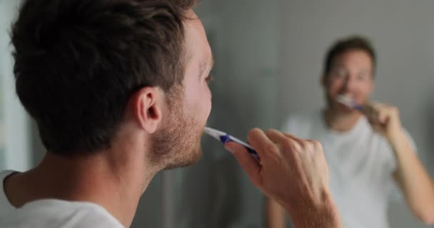 歯ブラシを使用して家庭用バスルームの鏡を見て歯を磨く男 — ストック動画