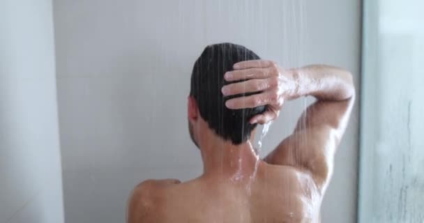 Man taking a shower enjoying showering under water falling from washing hairluxury rain shower head. Morning routine luxury bathroom. Male model showering. body care hygiene concept — Wideo stockowe