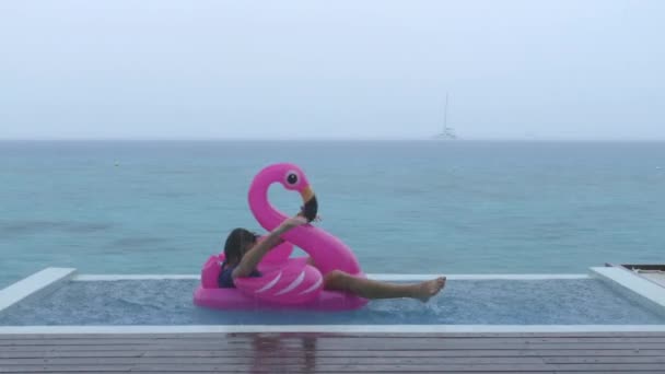 Funny fail video in vacation rain of man on flamingo float in luxury pool — Stockvideo