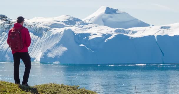 Podróż po arktycznym krajobrazie przyrody z górami lodowymi. Grenlandzki badacz turystyki przygląda się niesamowitemu widokowi fiordu lodowego Grenlandii dotkniętego zmianami klimatycznymi i globalnym ociepleniem. Góra lodowa w Ilulissat — Wideo stockowe