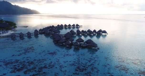 Günbatımında deniz kenarında mercan resiflerindeki bungalovların olduğu tatil cenneti havacılık videolarını seyret. Fransız Polinezyası, Tahiti, Güney Pasifik Okyanusu 'ndan hava videosu — Stok video