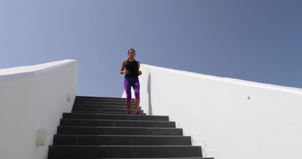 Woman running down stairs outside exercising. Fitness girl training legs and cardio outdoors with explosive exercises running up and down stairs. Shot at 59.94 FPS. SLOW MOTION — стоковое видео