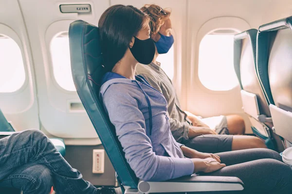 Couple tourists wearing face masks on travel vacation flight inside plane. Coronavirus safety prevention for passengers of flight. People lifestyle —  Fotos de Stock