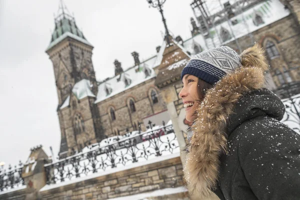 Ottawa winter city Asian woman walking by Canadian Parliament in Ontario, Canada. Travel tourist visiting popular attraction during snowfall wearing cold weather hat and jacket — Stockfoto