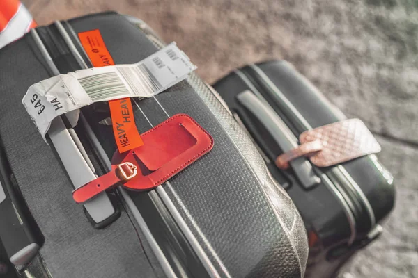 Two suitcases at airport with heavy tag closeup. Checked suitcase and carry-on luggage on the curbside ready for travel vacation with address tags. — Stock Photo, Image