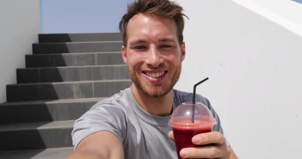 Selfie video by healthy eating man drinking beet juice smoothie in urban city background. Active lifestyle fitness runner eating breakfast vegetable shake on stairs after run — Vídeos de Stock