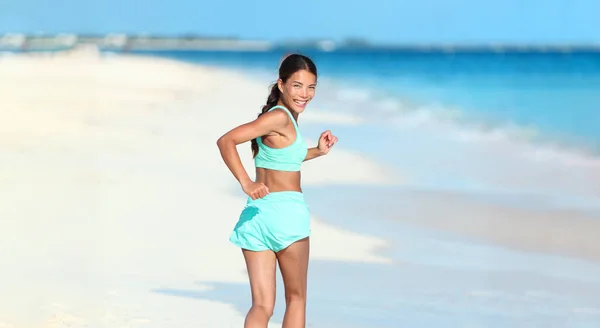 Szczęśliwy bieg fitness dziewczyna patrząc wstecz uśmiechnięty na plaży biegać aktywny zdrowy styl życia. Azji kobieta sportowiec ćwiczenia cardio ćwiczenia w lecie na świeżym powietrzu — Zdjęcie stockowe