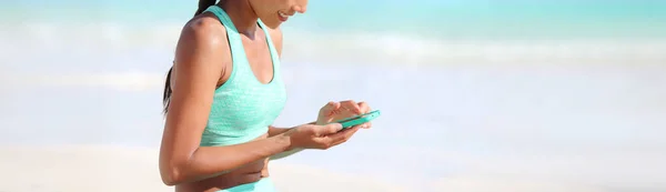 Fitness σε απευθείας σύνδεση app ταιριάζει ενεργό κορίτσι χρησιμοποιώντας το κινητό τηλέφωνο για heatlh και την παρακολούθηση της προόδου άσκηση στη συσκευή τεχνολογίας. Πανοραμική σημαία της αθλήτριας που παρακολουθεί το άθλημα της — Φωτογραφία Αρχείου
