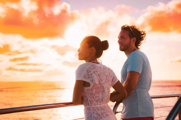 Sunset cruise romantic couple watching view from boat deck on travel vacation. Silhouette of man and woman tourists relaxing on outdoor balcony of ship — ストック写真