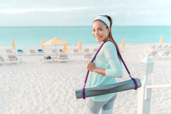 Yoga teacher going to beach with exercise mat to give outdoor yoga or pilates class at hotel resort in tropical destination by the ocean — Zdjęcie stockowe