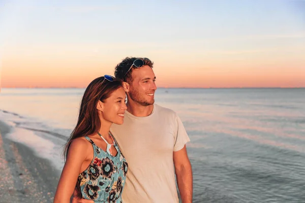 Ein gemischtes Paar spaziert am Strand von Florida und beobachtet den Sonnenuntergang. Junge glückliche Asiatin und kaukasischer Mann lächeln natürliche Schönheit Outdoor-Porträt. USA-Urlaub — Stockfoto