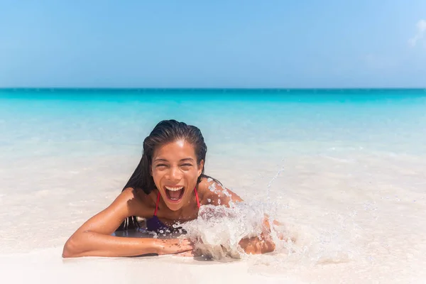 Happy Asian bikini woman laughing playing in splashing wave on Caribbean beach. Summer fun vacation — Stock Photo, Image