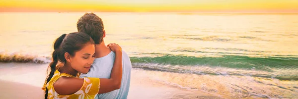Couple amoureux étreinte panorama bannière. Femme asiatique embrasser copain relaxant sur la plage regarder coucher de soleil amour et tendresse pendant les vacances d'été Voyage — Photo