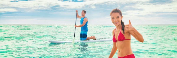 Tatil eğlencesi yaz sporları eğlence plajı su sporları çifti panoramada raketbol oynuyor. Havai 'de stand-up panolarında kürek çeken insanlar. Karışık ırktan beyaz bir kadın. — Stok fotoğraf