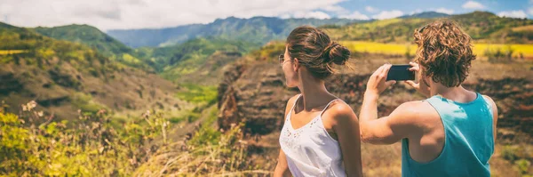 Un par de turistas tomando fotos telefónicas del paisaje natural de Hawaii con la aplicación de la cámara del teléfono inteligente. Viajes estilo de vida personas disfrutando vacaciones de verano —  Fotos de Stock