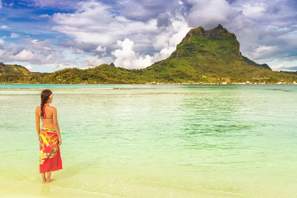 Slunce tropické pláže luxusní cestování dovolená turistka relaxační nošení červené pareo zakrýt sukni jako plážové oblečení na Tahiti. Pohled na ostrov Bora bora ze soukromého motu. Sluníčko a oceán — Stock fotografie