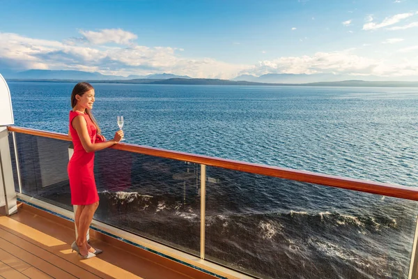 Cruise luxury travel lifestyle woman on fancy Europe vacation. Asian elegant lady drinking champagne glass watching sunset on private balcony deck