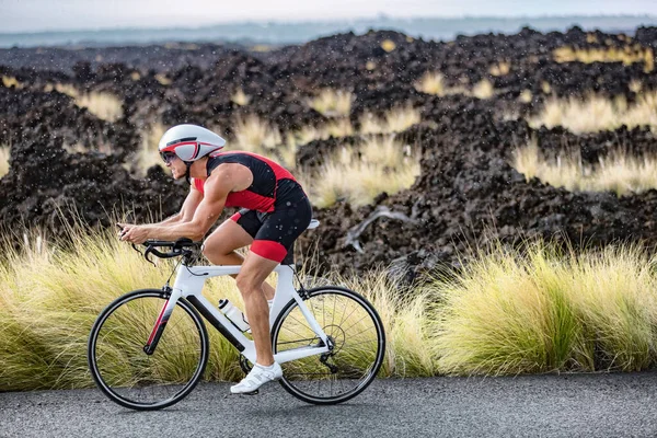 Ciclismo triatleta hombre ciclismo bicicleta de carretera bajo la lluvia durante la carrera de triatlón en Hawaii paisaje de la naturaleza. Entrenamiento de resistencia de entrenamiento de deportistas al aire libre en Kailua-Kona, Big Island, Hawaii, Estados Unidos — Foto de Stock