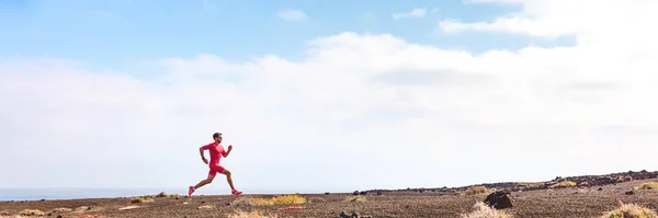 Atleta corriendo hombre atleta en carrera de triatlón. Héroe vista de perfil del corredor en la colina entrenamiento hiit entrenamiento ir cuesta arriba. Paisaje panorámico fondo de cultivos — Foto de Stock