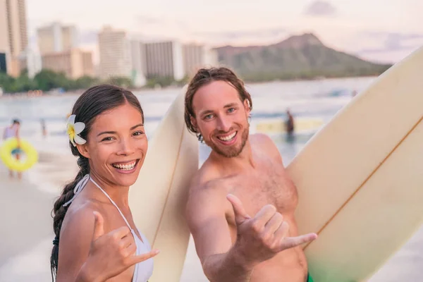 Hawaje wakacje surferzy para robi shaka hawajski znak strony zabawy surfing w Waikiki Waikiki, Honolulu, Wyspa Oahu, Hawaje. Azjatka, biały mężczyzna ludzie na wakacjach — Zdjęcie stockowe