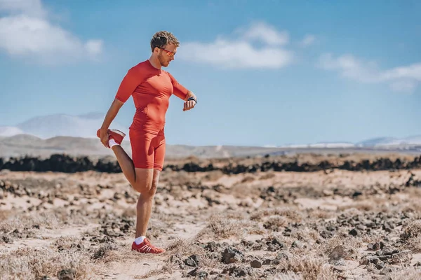 Löpare stretching ben med smartwatch för trail run. Idrottare kontrollerar smart sportklocka under uthållighet Ultra löpning race träning. man gör triathlon träning — Stockfoto