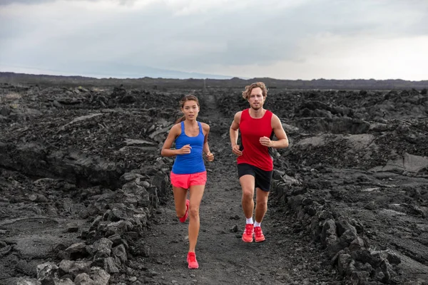 Sportowcy biegają parami biegaczy ćwiczących wytrzymałość w ekstremalnym terenie wulkanicznego krajobrazu. Biegaczka, Azjatka biegająca w stroju sportowym. Trening fitness do triatlonu — Zdjęcie stockowe