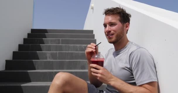 Beet Juice. Fitness sport man relax disfrutando después del entrenamiento desayuno por la mañana snack sentado en las escaleras al aire libre. Atleta bebiendo licuado de frutas rojas — Vídeos de Stock