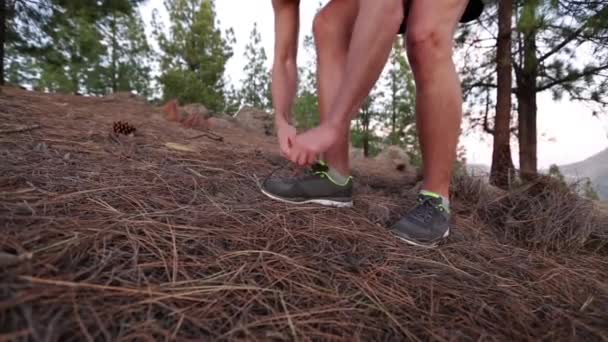 Corredor atando cordones en zapatillas corriendo en el bosque. Hombre atleta en carrera en fitness y el deporte concepto de vídeo — Vídeo de stock