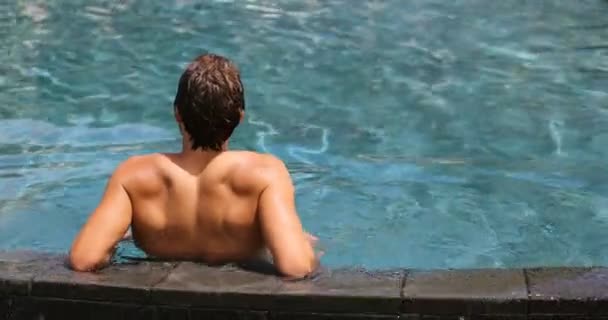 Yüzme havuzunda tatil yapan bir adam dinleniyor. — Stok video